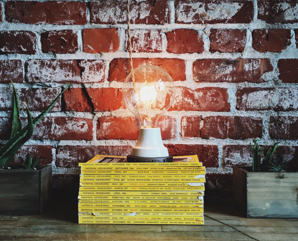 A glowing lightbulb sitting on a stack of books.